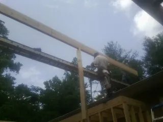 Carpenter setting a ridge beam over a new addition frame — Ice Dam Removal by Roofing Brothers in Orovada