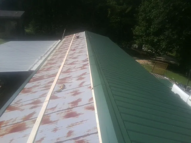 Old rusted panels beside newly installed green metal roofing — Wind Damage Roof Repair by Roofing Brothers in Orovada