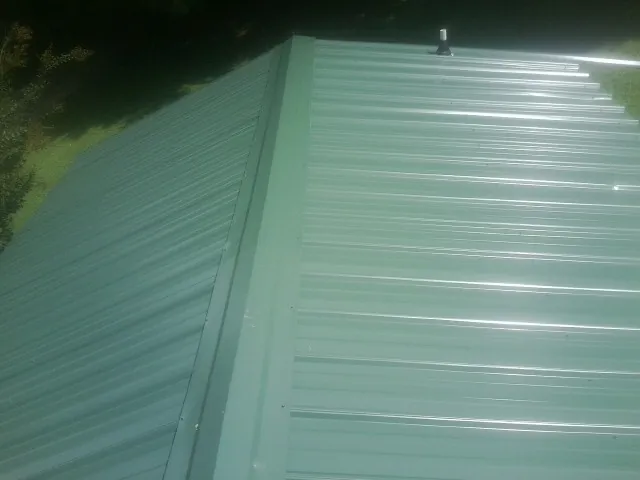New green metal panels meeting at the ridge of a roof — Flat Roof Repair work by our crew in Orovada