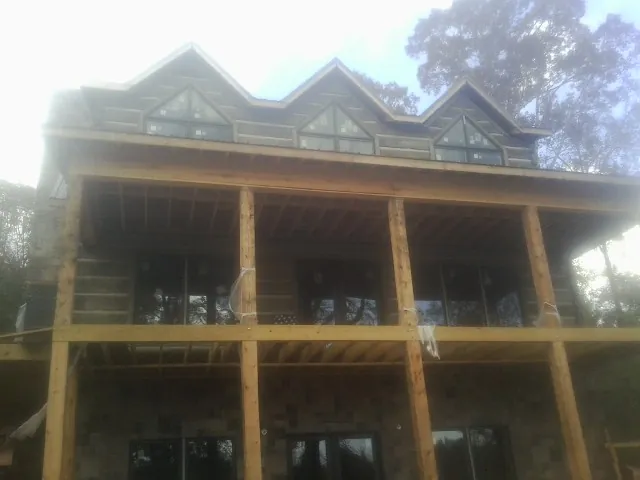 Dormers and porch framing on a large log home under construction — Roof Coating work by our crew in Orovada