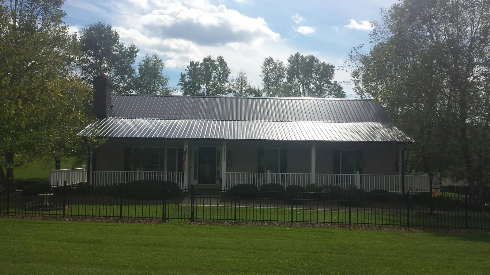Gray metal roof on a brick ranch with a full width front porch — Gutter Guard Installation work by our crew in Orovada