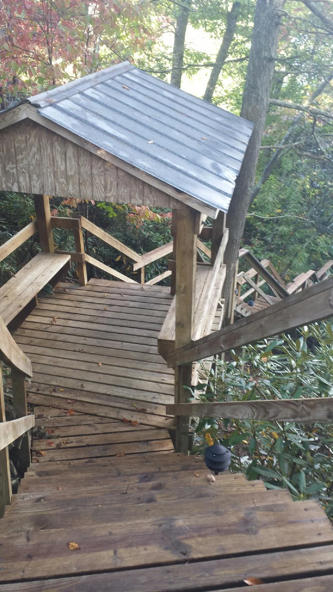 Metal roofed shelter over wooden steps on a wooded walkway — Skylight Repair & Installation work by our crew in Orovada