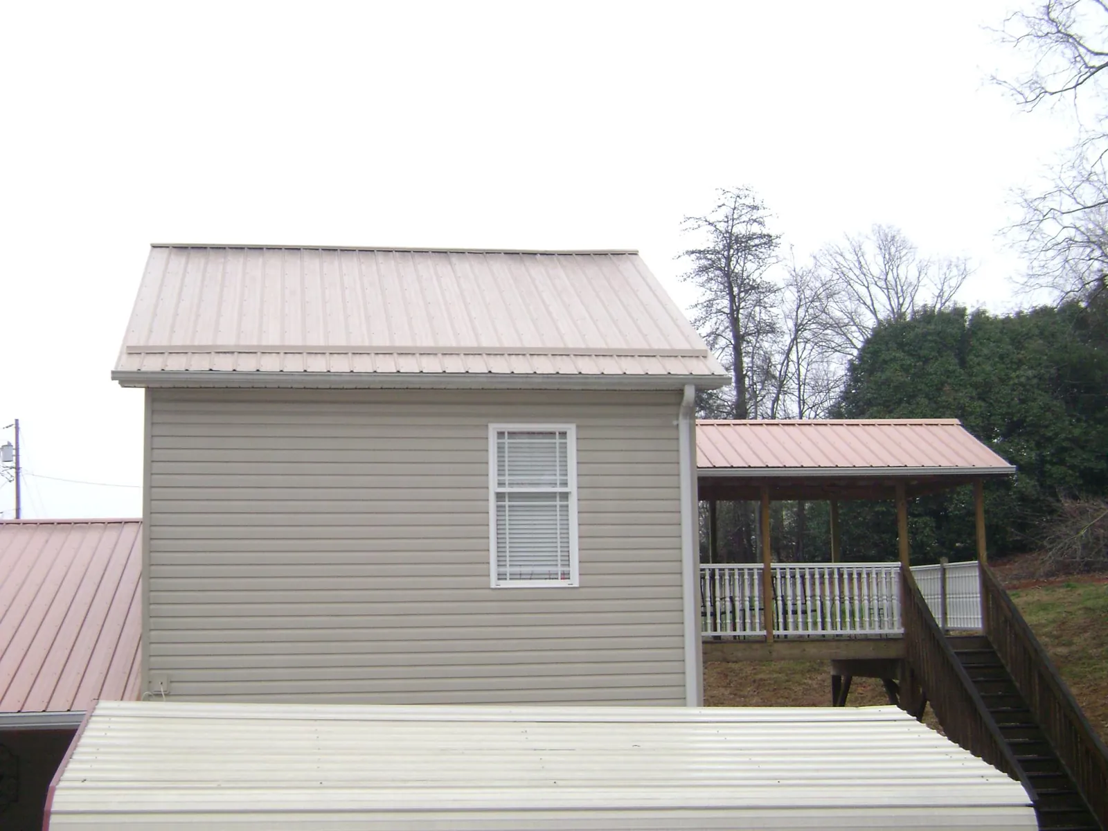 Tan metal roofs on a two story addition and attached porch, from a Roof Replacement job in Orovada