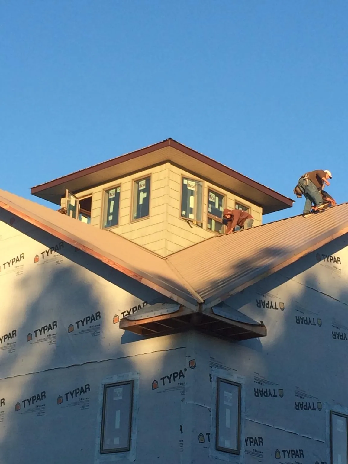 Roofers working around a rooftop cupola on a new metal roof at sunset — Roof Waterproofing in Orovada by Roofing Brothers